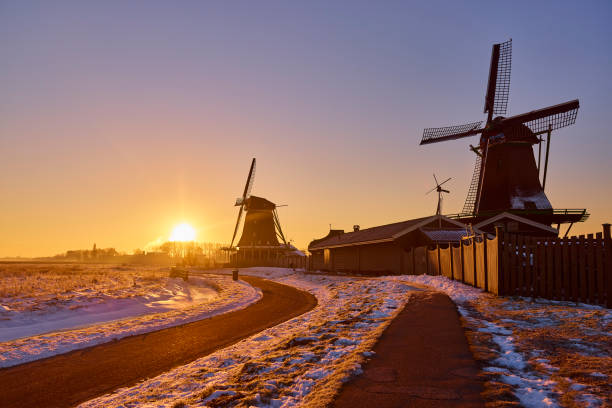 Zaanse Schans the historical village during winter, Netherlands. It’s early in the morning during sunrise. Everything is covered in snow and the water is frozen.