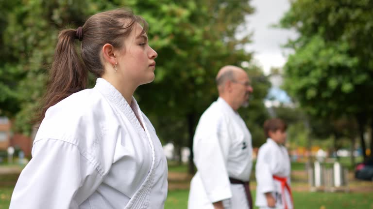 Teenage girl practicing karate/taekwondo movements during class at public park