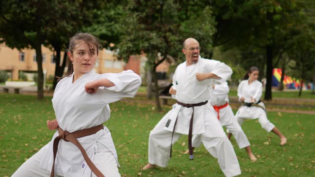 Teenage girl practicing karate/taekwondo movements during class at public park