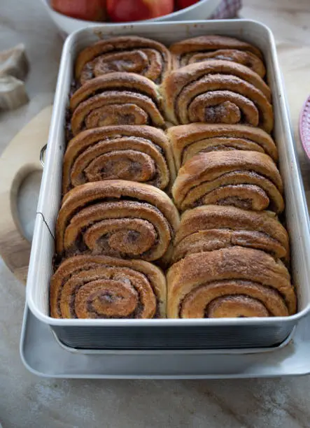 Homemade fresh baked danish cinnamon rolls. Caramelized with cinnamon sugar. Served warm and ready to eat in a baking pan on a table. Delicious autumn pastry.