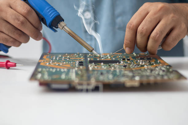 Technician using a soldering iron to repair a circuit board