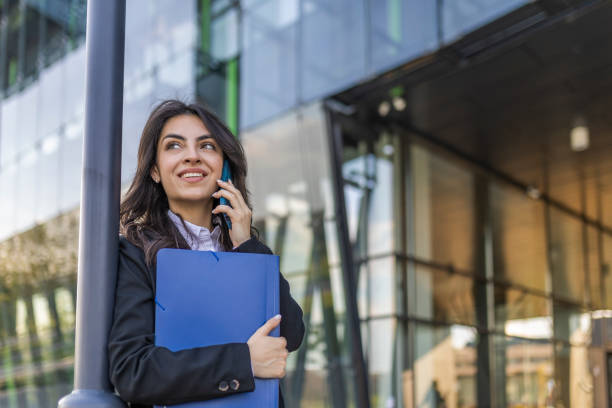 istock A girl in an interesting business conversation while standing leaning on a pole in front of a corporate building. 1726180077