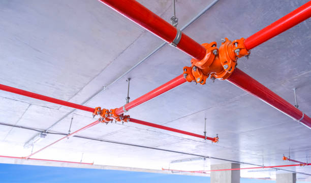 istock Red fire protective water pipeline system on concrete ceiling inside of parking garage building, View from below 1726194919