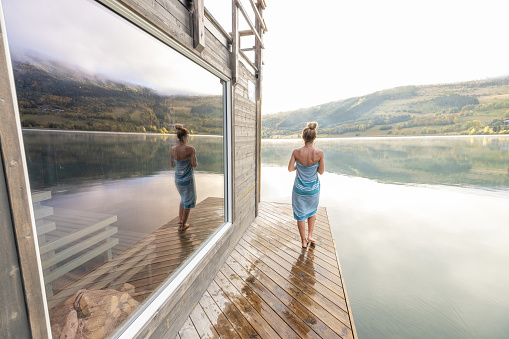 Young woman relaxing outside a in floating sauna, she contemplates nature