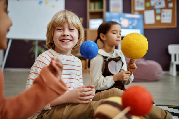 istock Cute blonde boy holding planet model in preschool class 1726212702