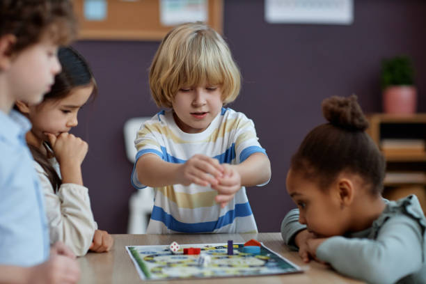 Diverse group of little kids playing board game together in preschool