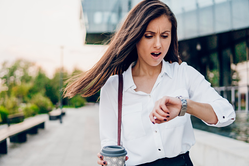 Businesswoman looks at her watch and rushes to work.