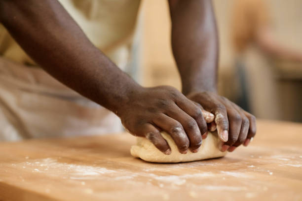 Close up of young Black man kneading dough making fresh bread in artisan bakery