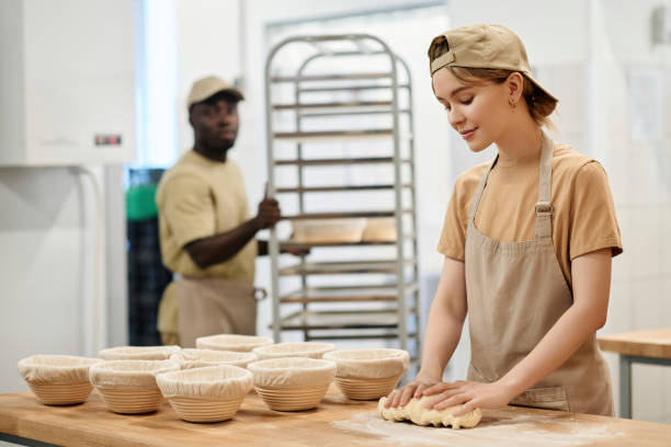 istock Smiling young woman working in bakery and kneading dough for bread 1726218645