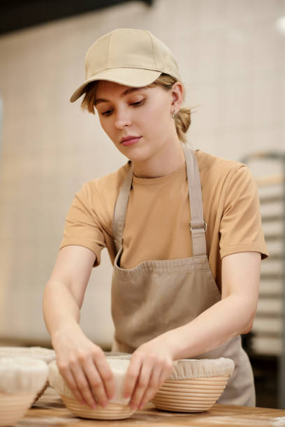 istock Young woman putting fresh dough in bowls working in bakery kitchen 1726218647