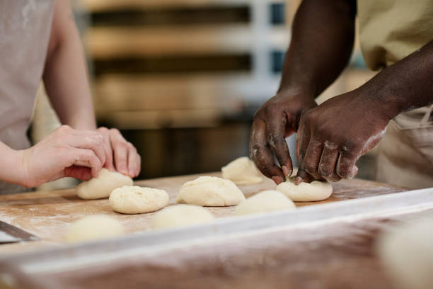 istock Close up of two people preparing fresh buns in bakery and working with dough 1726218690