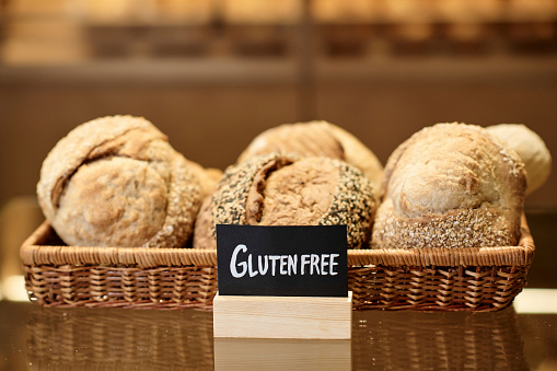 Background image of fresh breads in basket in artisan bakery with Gluten free sign, copy space