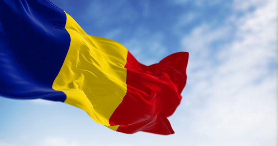 Romania national flag waving in the wind on a clear day. Three vertical stripes of equal width: blue, yellow, and red. 3d illustration render. Rippling fabric. Selective focus