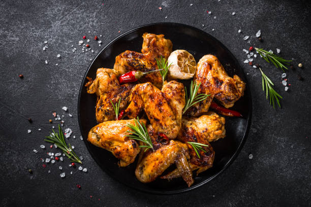 istock Grilled chicken wings with spices at black table. 1726224468
