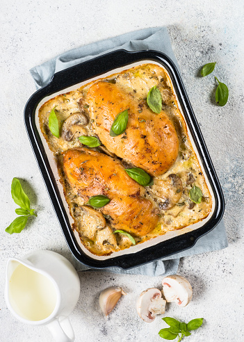 Baked chicken fillet with mushrooms in cream sauce. Top view on white kitchen table.