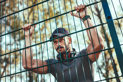 Young man with headphones is resting after training in autumn nature.