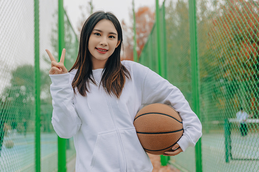 Asian girl in white hoodie on the basketball court in the the University