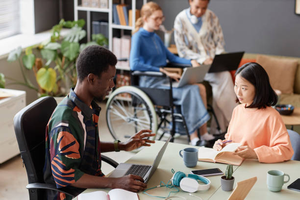 istock Colorful two young professionals collaborating on project at meeting table 1726237363