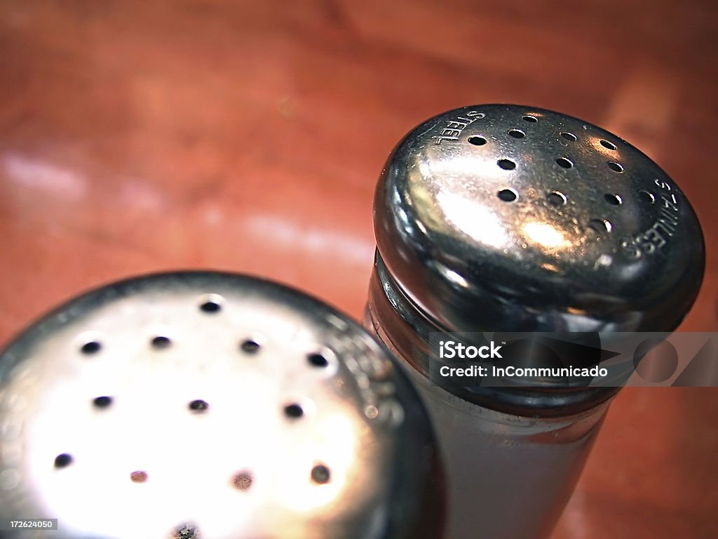 Salt & Pepper 2 Macro view of the stainless steel tops of a pair of salt & pepper shakers of clear glass.  Focus is on the right shaker. Breakfast Stock Photo