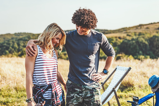 Happy young couple enjoys a sunny day in nature,  hugging each other.