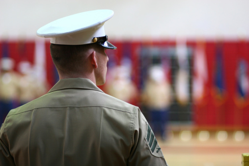 On a wooden table lay a camouflage military cap, a pair of army medallions, metal handcuffs and a blue pen with a piece of paper. Concept: law enforcement, military authority.