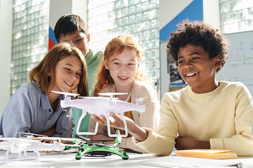 Diverse group of happy children looking at quadcopter with spinning propellers