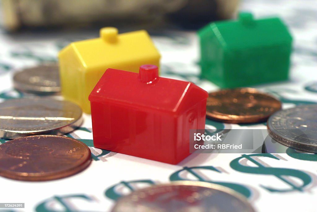 Monopoly houses surrounded by coins sitting on dollar signs houses and money 401k - Single Word Stock Photo