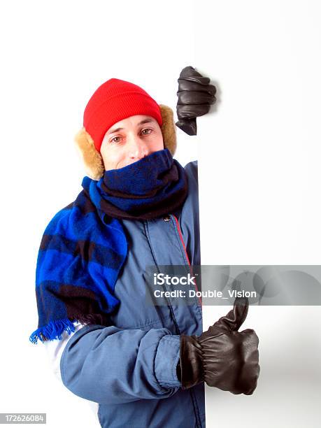 Hombre En Invierno Retención De Engranaje En Blanco Signo Dando Pulgares Arriba Gesto De Foto de stock y más banco de imágenes de Abrigo