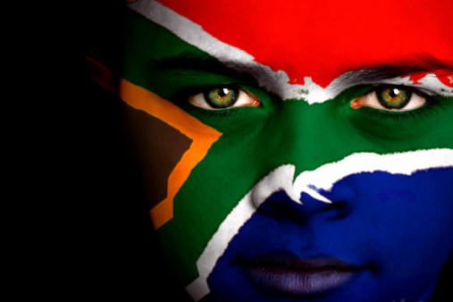 Portrait of a boy with the flag of South Africa painted on his face