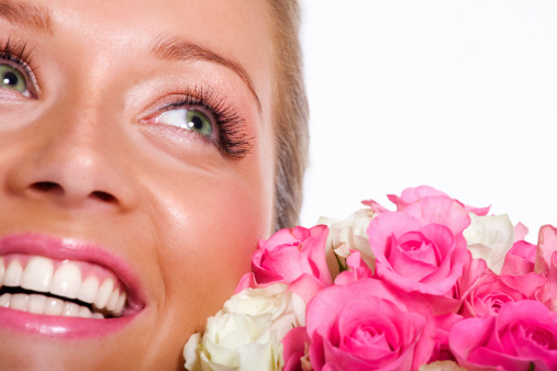 Close-up of female face with pink roses. Focus on flowers and one eye. Space for copy.