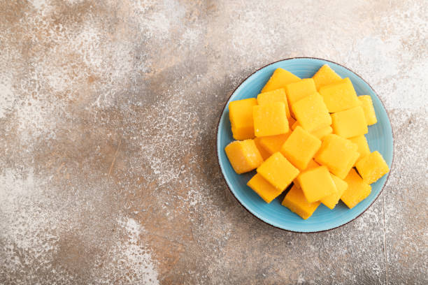 istock Dried mango cubes on blue plate on brown concrete, top view, copy space. 1726265570