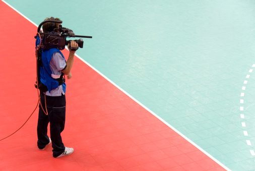 A sports television cameraman stands by the court.