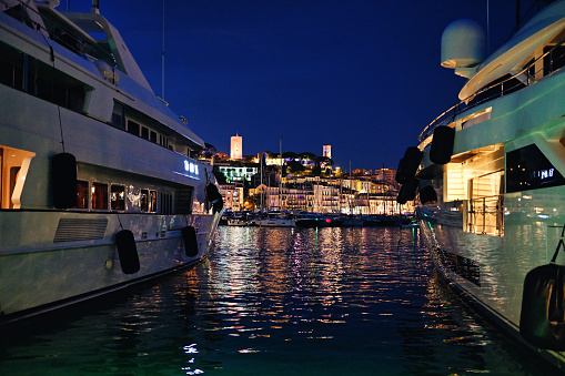 View of the sea port of Cannes with moored yachts at night, France. Cityscape on the background, illumination