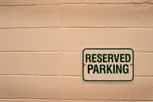 Brick wall with reserved parking sign.