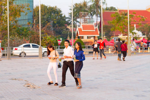 Candid capture of walking Young Laotian adults on promenade at Mekong river i n Vientiane stock photo
