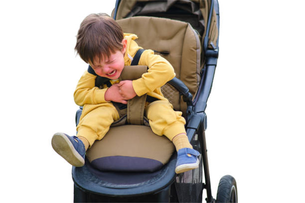 istock The crying baby in the stroller creates a sad expression on his face in the park, isolated on white background. Kid aged two years (two-year-old boy) 1726294061