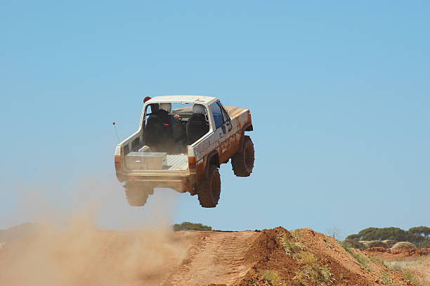 Truck driving off a ramp while off-road racing stock photo