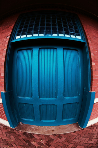 Large wooden door.  Fisheye lens makes door appear as though it's bulging under great pressure and stress from inside.