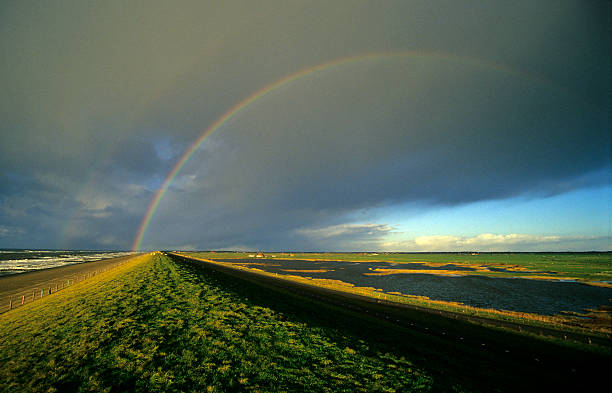 arcobaleno sopra un argine - rainbow rain polder sea foto e immagini stock