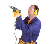A worker in anti-noise headphones with a drill.