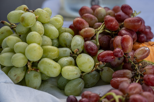 Party guests have appetizing bunches of green and purple grapes set up on a buffet table.