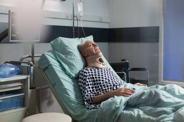 älterer mann liegt im krankenhausbett und trägt cerival-halsband - iv bruise stock-fotos und bilder