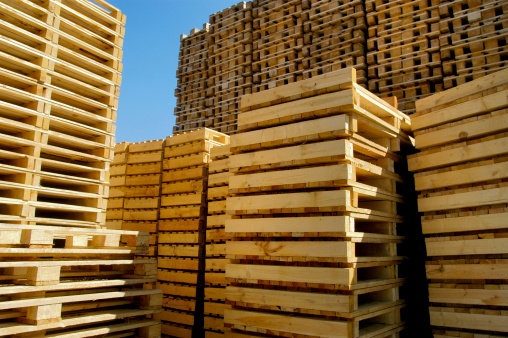 Many empty wooden pallets stacked in warehouse