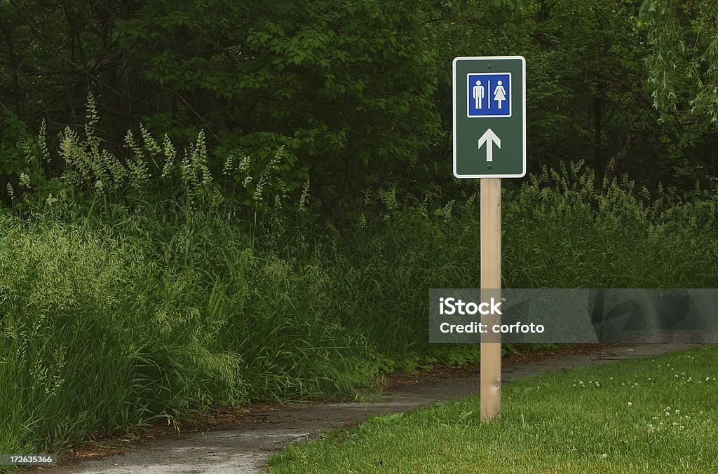 Behind the Trees Sign for a restroom somewhere in the woods Outhouse Stock Photo