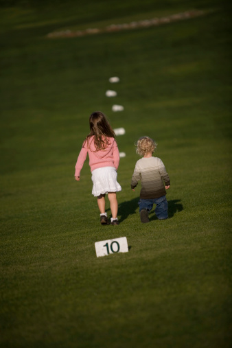 Two small children strolling along a driving range