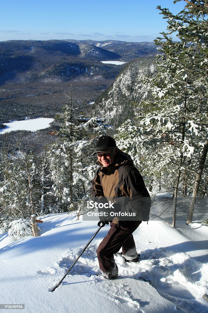 Senior Man Walking in Snowshoe Trail in Winter Happy senior in a snowshoe trail looking at the view. (Vallee du bras du nord, St-Raymond, Quebec) 55-59 Years Stock Photo