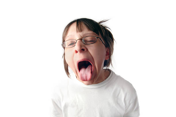 Horizontal image of a young girl who obviously has a bad taste in her mouth. She is sticking her tongue out as far as she can and her eyes are squinted shut. 