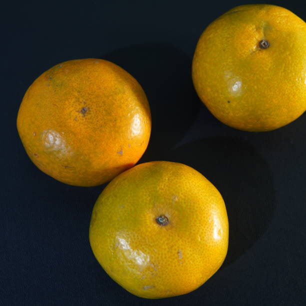 pomarańczowy owoc na czarnym tle - cynga zdjęcia i obrazy z banku zdjęć