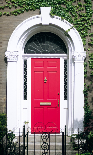 A vertical shot of a vintage red front door of a white building in Valetta, Malta