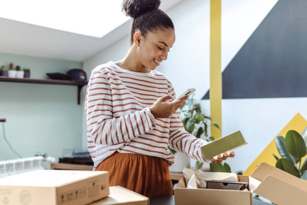 istock Young African-American holding cardboard boxes and using smart phone 1726379255